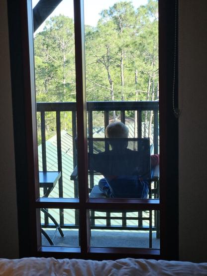 Kid sitting on balcony looking at trees