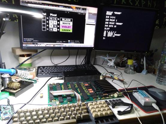 Apple II mainboard, power supply and keyboard on a table, connected to LCD monitor display a listing of BASIC program.