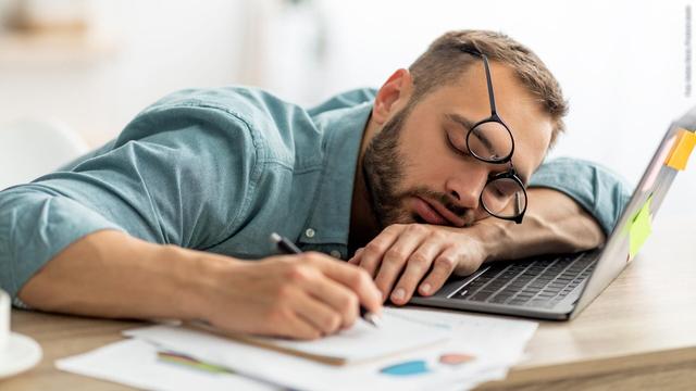 Ein Mann ist auf seinem Laptop mit einem Stift in der Hand eingschlafen. Symbolbild für Mittagsschlaf oder Powernap während der Arbeit.  (Foto: Adobe Stock, Prostock-studio)