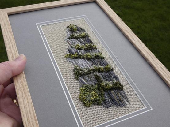 Same artwork held in the artist's hand for scale and viewed on another an angle to show texture.