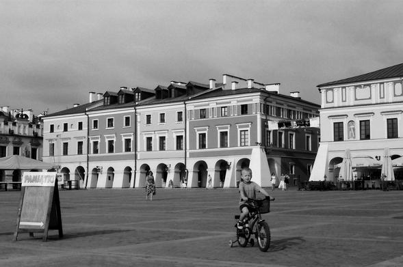 Rynek z kamienicami, dziecko jedzie na rowerze