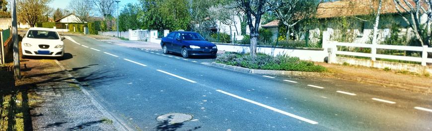 Véhicule blanc garé comme une merde, bloquant toute la largeur du trottoir. En face se trouve une place libre à environ une dizaine de mètres.