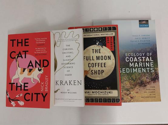 A spread of 4 books: The Cat and the City, Kraken, The Full Moon Coffee Shop, and Ecology of Coastal Marine Sediments.