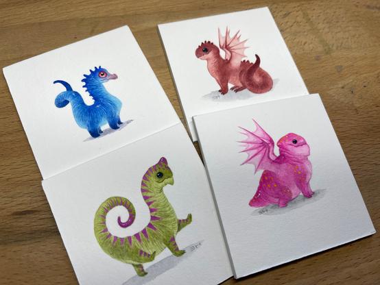 four paintings of tiny dragons, one blue, one red, one green with pink stripes, and one pink with yellow dots!