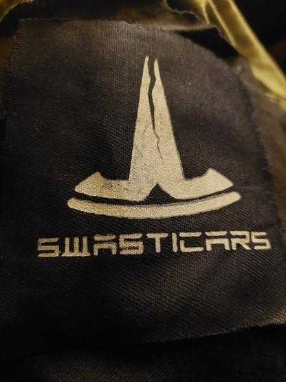Cracked, upside-down Tesla logo, with the caption 'Swasticars'.