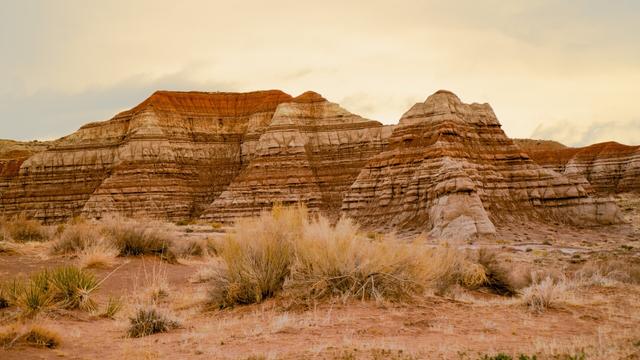 A scenic landscape view of the Grand Staircase - Escalante National Monument in Utah. The image shows sedimentary rock exposed in defined layers.