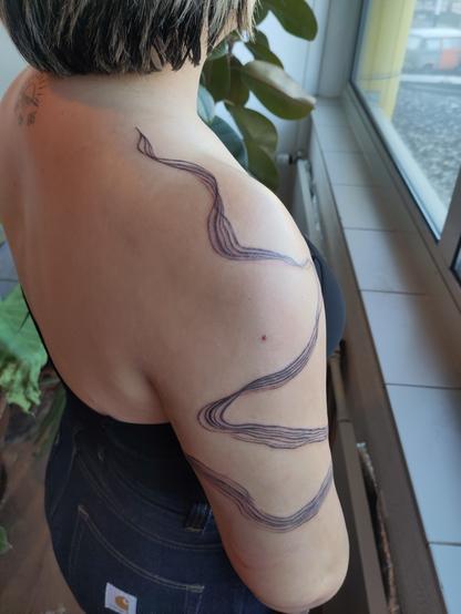 Brushstroke tattoo on an arm and shoulder