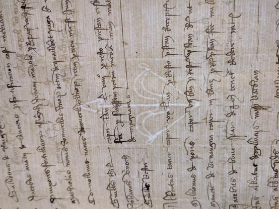 Un filigrane en forme d'arc avec une flèche, en transparence derrière des écritures anciennes