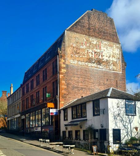 A large, brick-built former whisky warehouse with a ghost sign on its gable end.