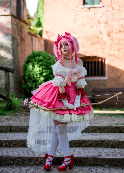 A cosplayer of Madoka Kaname dressed in a pink and white frilly outfit poses outdoors on a stone pathway. They hold a decorative bow with a flower-tipped arrow and stand with a poised, focused expression. The background features an old building with greenery, adding a rustic charm to the scene.

tags ignore: madoka kaname cosplayer pmmm puella magi madoka magica photo photography model cosplayphoto cosplayphotography cosplaymodel cute kawaii kofi throne italy anime manga maho shojo magical girl mahou shoujo mahoushoujomadokamagica mahoushoujo mahoshojo