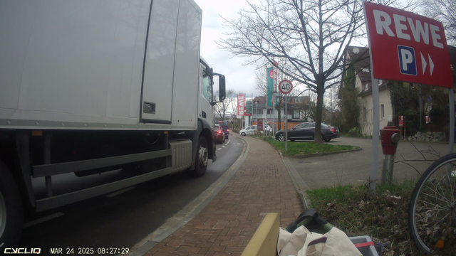 Radschuitzstreifen vor einer Ampel. Die wartenden PKW-Fahrer lassen Platz zum vorbeifahren. Der gerade einrollende LKW wird von seinem Fahrer fast am Bordstein entlang gelenkt - auf dem Radfahrschutzstreifen