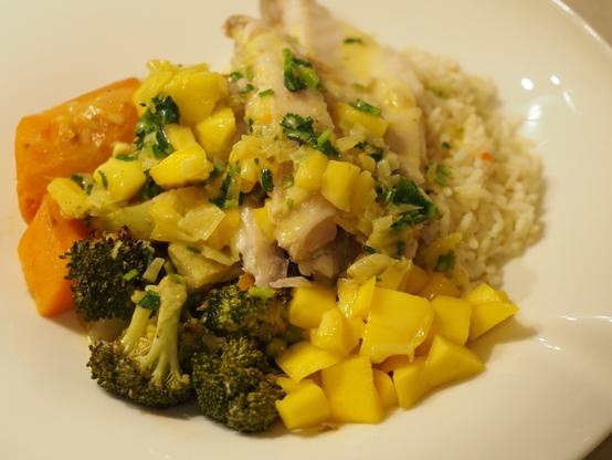 Das fertige Gericht im Ofen gegarter Süßkartoffel, Brokkoli und Filet vom Karpfen neben etwas Reis, frischrr Mango und einer Mango-Sauce