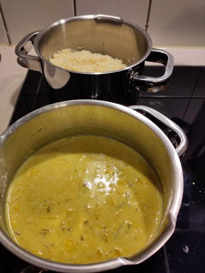 Zwei kleine Töpfe auf einem länglichen Kochfeld. Im Vordergrund die Mango-Sauce, dahinter der Topf mit gekochtem Reis.