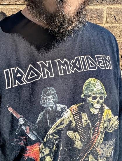 A black longsleeve shirt displaying the Iron Maiden logo. It also shows their mascot Eddie dressed in military uniform as well as a skeleton also wearing an army uniform.