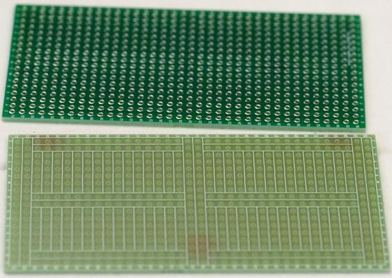 A photograph of 2 perforated prototyping printed circuit boards, one showing the front and the other the back.

The boards are the typical green of fiberglass boards, with shiny exposed pads on the underside, and labels for rows and columns  silkscreened in white on both sides.  There are also silkscreened outlines on the front of the board to indicate the pattern of joined pads on the back.