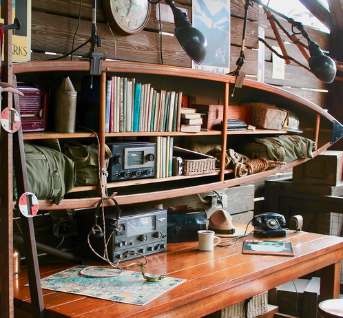 Office with National Parks posters and a bee smoker and two shortwave ham radios, plus a backpack and outdoors book and an old phone, plus a mug and rope and hardhat -- from Disney California Adventure