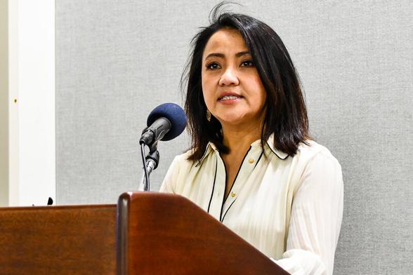 Patsy Widakuswara behind a lectern and microphone