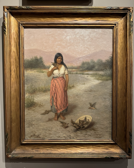 photo of the panting framed on display at museum portrait of a young Pomo woman in white top and pink striped skirt standing in native landscape, holding a wild dove in right hand while looking down at other doves scattered around and sitting inside a woven Pomo basket in ground