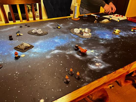 My dining table covered with a huge space gaming mat, swarming with tiny space ships.