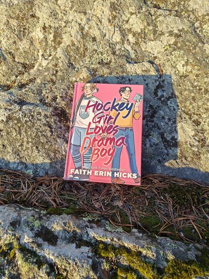 Kuvassa Hockey Girl Loves Drama Boy -kirja kuvattuna kalliolla.
