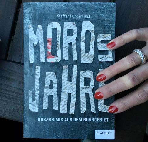 Hand mit blutroten Fingernägeln liegt am Rand des Buchcovers von MORDsJAHRE.