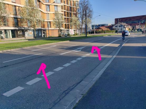 Straße mit Fahrradweg auf der Fahrbahn, Geradeaus- und Linksabbiegerspur rechts neben dem Straßenbahngleiskörper. Auf der linken Hälfte der Geradeausfahrspur ist eine lange schwarze Linie zu sehen.