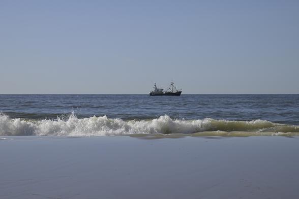 The image depicts a serene beach scene with a clear blue sky and calm north sea waters. In the foreground, gentle waves roll onto the sandy shore, creating a frothy white foam as they break. The sand appears smooth and light-colored, reflecting the sunlight. In the background, a fishing boat is visible on the horizon, slightly to the right of center. The boat is dark-colored, with a visible structure and equipment, indicating it is likely engaged in fishing activities like shrimp fishing. The water is a deep blue, transitioning to lighter shades near the shore, and the horizon is clear, with no visible landmasses. The overall composition is tranquil, with the boat providing a focal point against the vastness of the sea and sky.

Provided by @altbot, generated privately and locally using Ovis2-8B

🌱 Energy used: 0.195 Wh