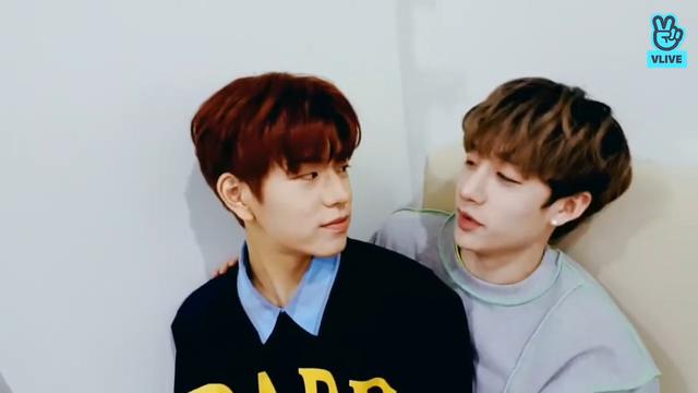Chan has a hand on Seungmin's shoulder as Seungmin sits on his lap and they look at each other