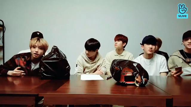 skz members sit behind a low table. Lee Know is behind Han, who he's just dragged into his lap