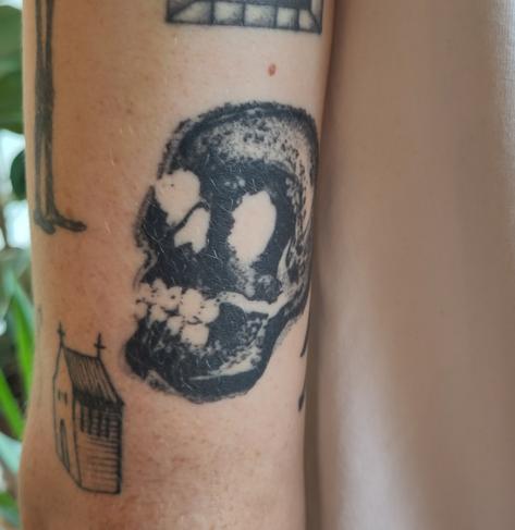 Healed skull tattoo on the back of an upper arm