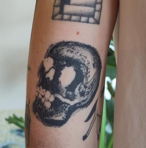 Healed skull tattoo on the back of an upper arm