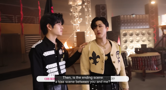 Seungmin and Changbin on the set of the LALALALA MV. Seungmin's hand is on Changbin's shoulder. Caption: "Then, is the ending scene a kiss scene between you and me?"
