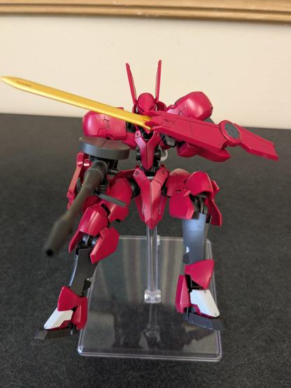 The HG Grimgerde on a stand appearing to be falling while guarding its chest and aiming a gun at the viewer
