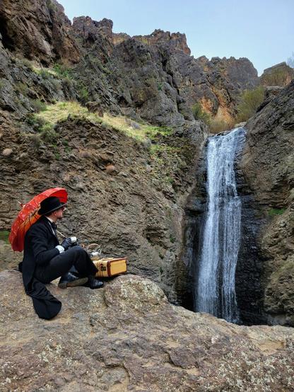 Once again, I've found myself in the middle of nowhere, far from civilization, but taking a little break in my search with a bit of tea. Perched on a rock edge and dressed in my best antique French tuxedo and bowler, I sip on tea while watching the falling water of a waterfall before me. The tails of my jacket drape on the rocks behind me and a vintage Samsonite suitcase acts as a small table to hold my teapot. The brisk winds whip down the chasm caused by eons of water slowly eroding away at the landscape and I huddle under my red parasol, resting on my shoulder, to hide from chill of the wind lapping at my face. The warmth of the tea sustains me (and the many layers of antique wool).