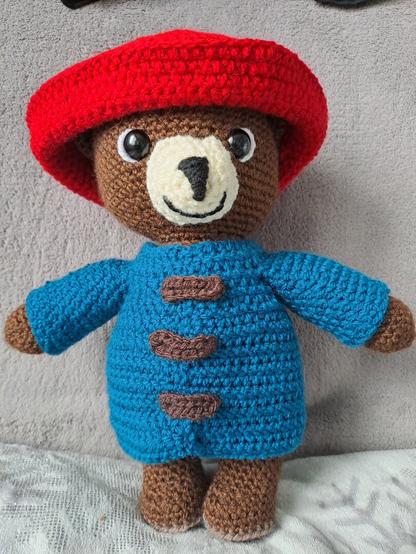 Ourson Paddington au crochet : ours brun avec une veste bleue et un chapeau rouge.