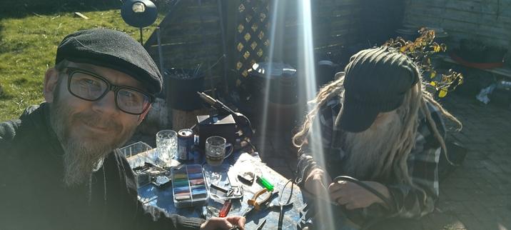 Two dudes in the sun at a small desk with cables and tools