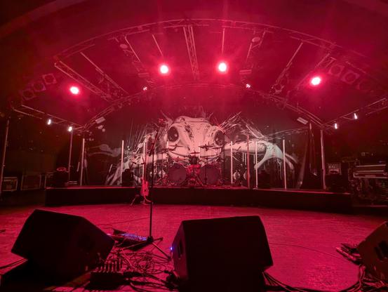 Empty stage in red lights. A huge green frog on the back wall