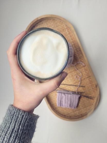 ENG A knitting project - lilac socks, the ribbing is just finished - and a cappuccino in a small handmade cup

DEU Ein gerade begonnenes Strickprojekt, eine Socke aus Wolle in hellem Lila, und ein Cappuccino in einem kleinen, handgetöpferten Becher
