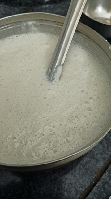 A steel box. In the box you can see 15 hr fermented dosai batter, all tangy and bubbly with a steel ladle.