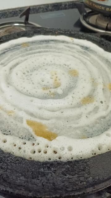 Dosai made with homemade batter being made on hot cast iron pan, with Jharna ghee dollops pooling in places.