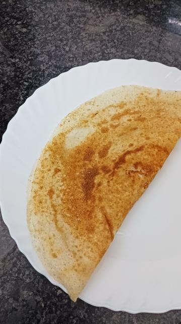 A freshly made, golden brown dosai on a white plate.