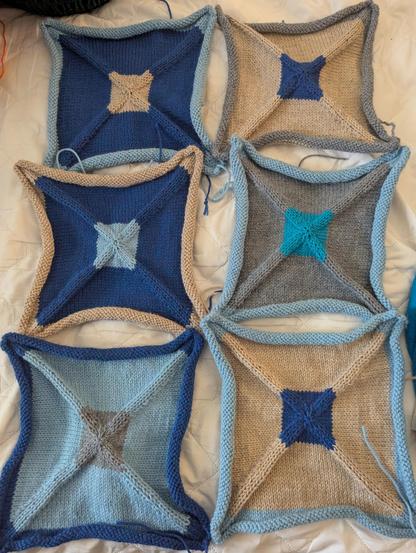 A photo of six colorful knitted squares in various combinations of blue, grey and beige.