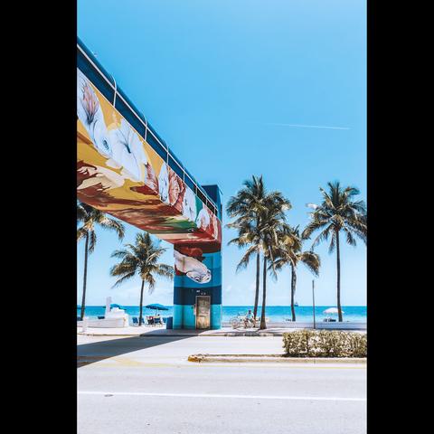 Street photo in color of a man sitting  under a blue sky in the street of Fort Lauderdale, Florida, USA