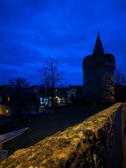 Hexenturm in Gelnhausen im dunkeln. Im Vordergrund eine alte Mauer