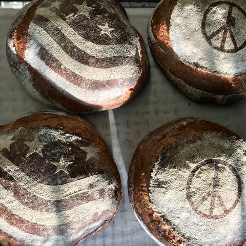 Large round loaves of bread with American flags and peace signs stenciled on them.