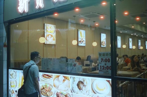 Man infront of Dim Sum restaurant at night.