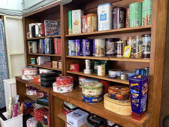 Wooden shelves filled with brightly painted tins of all shapes and sizes - round, cylindrical, square, etc.