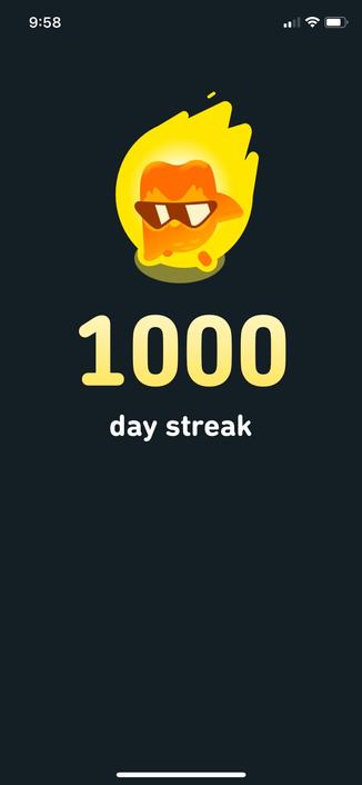 1000 day streak card in duolingo with Duo bathed in fire wearing sunglasses and doing a superhero landing