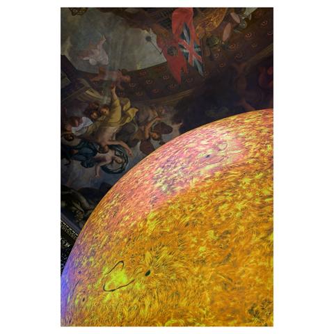 Colour picture of Luke Jerram's art display called Helios at The Painted Hall in Greenwich. The picture shows part of the illuminated sun globe with The Painted Hall's decorated ceiling in the background