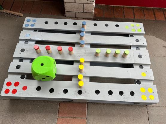 Zu sehen ist ein Mensch-Ärger-Dich-Nicht-Spiel, dass aus einer Holzpalette gebaut wurde.